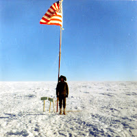 A person standing in the snow holding a flag

Description automatically generated